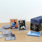 Collection of trading cards and BCW card sleeves on a wooden surface with a white background